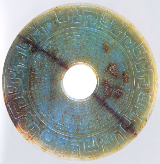 Disk of green jade with centre hole and stylized animal motives on the edge
